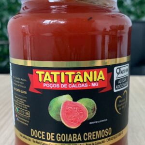 Frasco de doce de goiaba cremoso com rótulo colorido destacando ingredientes e informações da marca Tatitânia, sobre fundo de madeira.